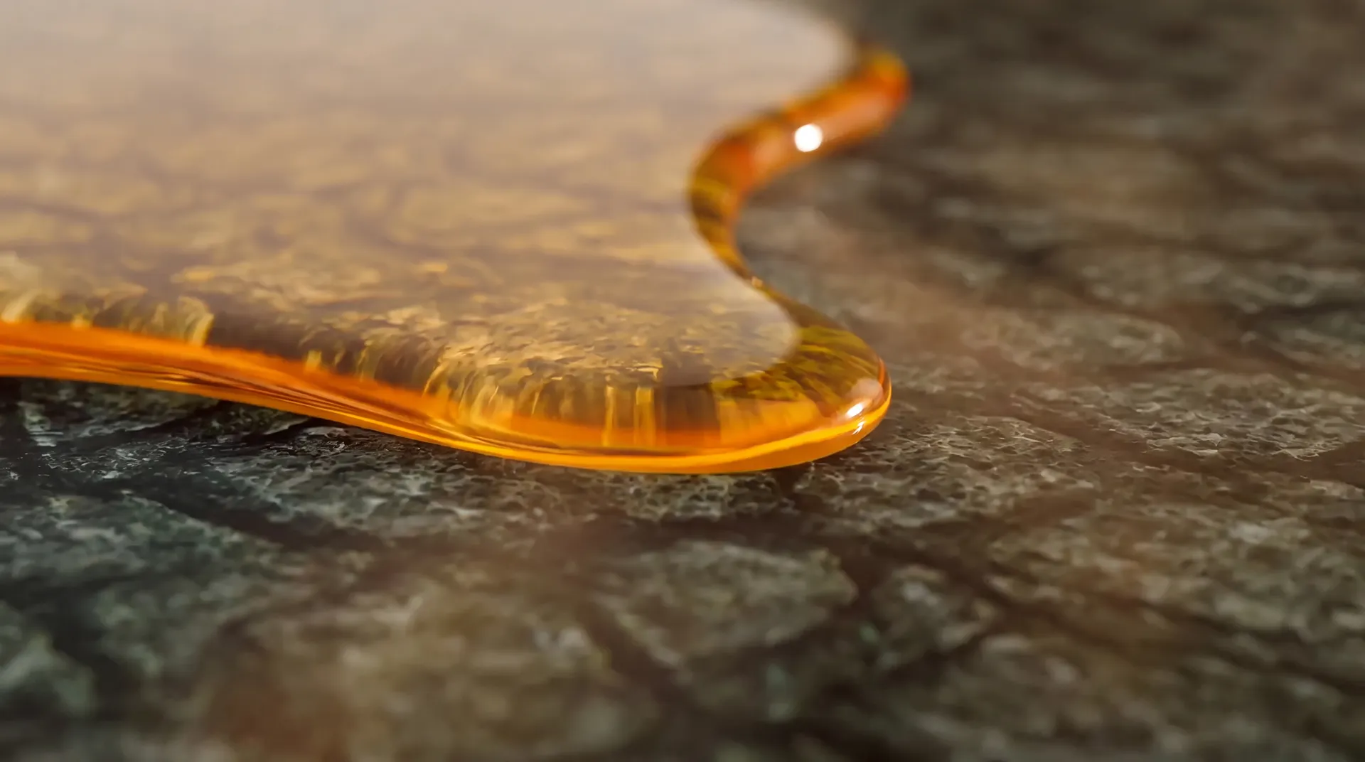 Golden botanical oil pooled on deep green stone